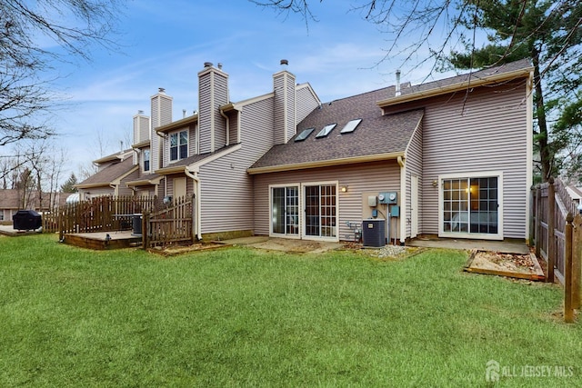 rear view of property featuring cooling unit, a shingled roof, fence, a lawn, and a chimney