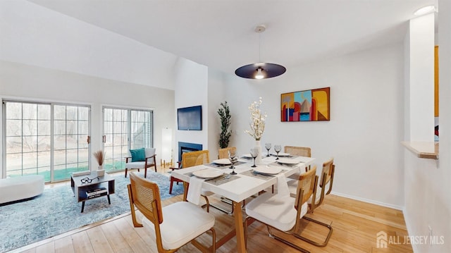 dining space featuring light wood-type flooring, a fireplace, and baseboards