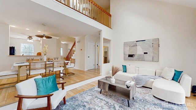 living room with recessed lighting, a towering ceiling, wood finished floors, baseboards, and stairs