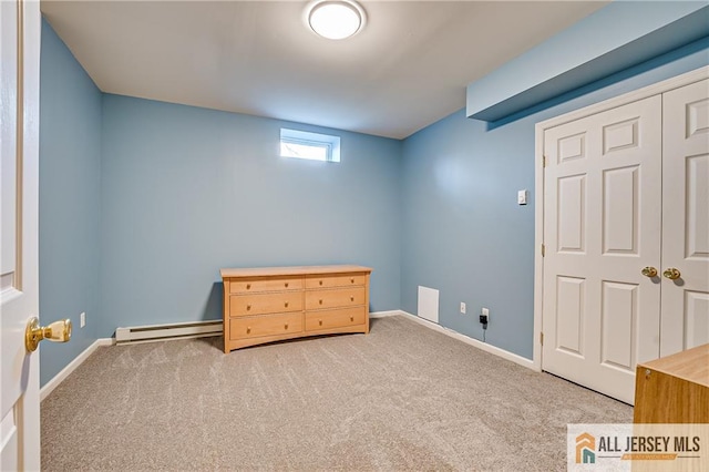 unfurnished bedroom featuring a baseboard radiator, carpet flooring, and a closet