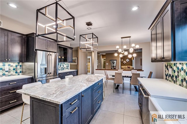 kitchen featuring tasteful backsplash, hanging light fixtures, a center island, light stone countertops, and high end fridge