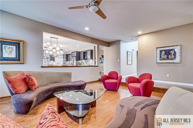 living room featuring wood-type flooring and ceiling fan with notable chandelier