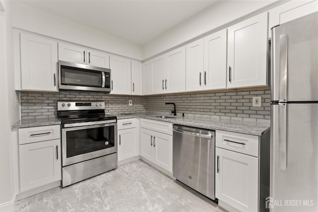50 Ellen Heath Dr, Matawan, NJ 07747 - kitchen featuring appliances with stainless steel finishes, light marble finish floors, white cabinets, and tasteful backsplash