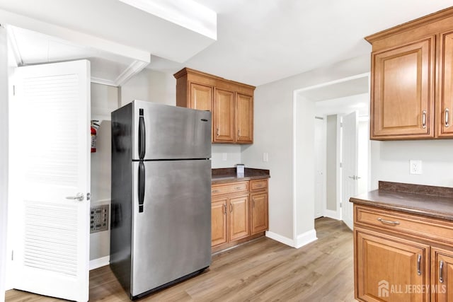 kitchen with light wood finished floors, dark countertops, brown cabinets, and freestanding refrigerator