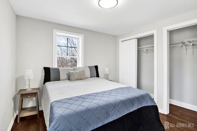 bedroom with wood finished floors, multiple closets, and baseboards