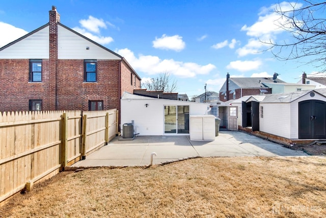 rear view of property featuring a storage unit, fence, an outdoor structure, and a patio area