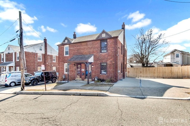 view of front of home featuring fence, brick siding, and a chimney