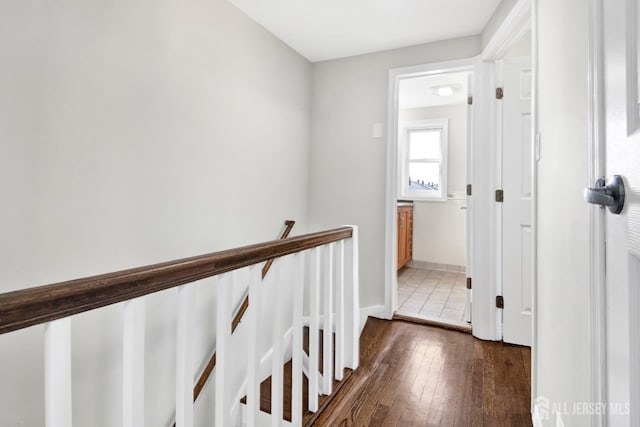 hall featuring hardwood / wood-style flooring, an upstairs landing, and baseboards