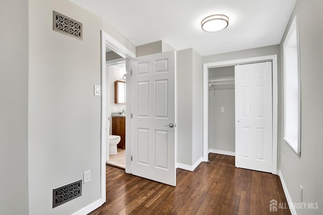 unfurnished bedroom featuring dark wood finished floors, baseboards, and a closet