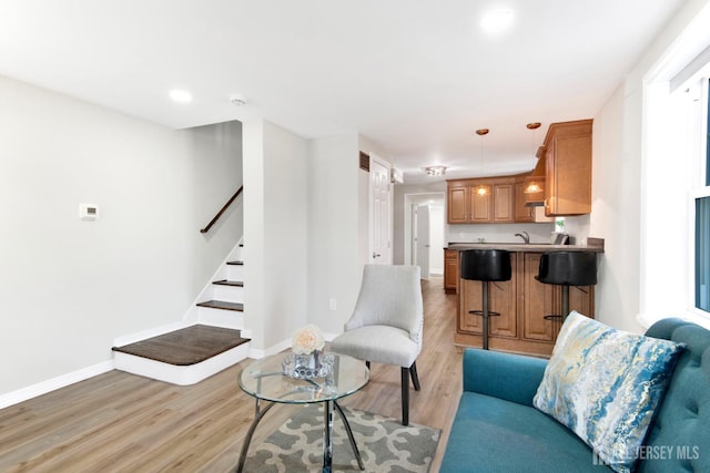 living area with recessed lighting, stairway, baseboards, and light wood-style floors