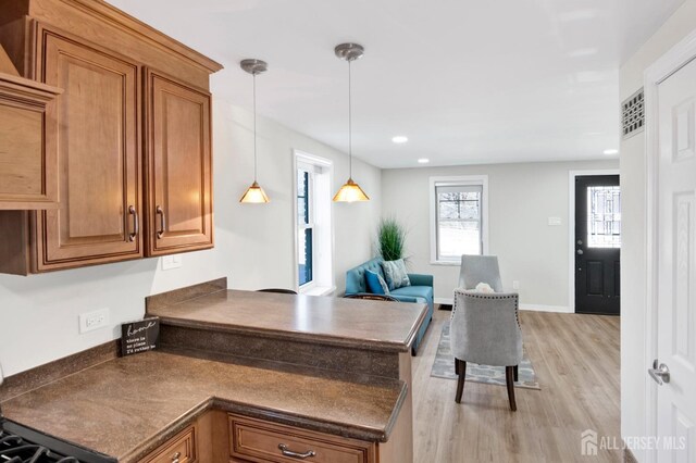 kitchen with dark countertops, brown cabinetry, and light wood-type flooring