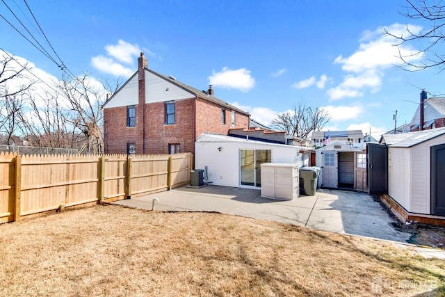 back of property with fence, central AC, an outdoor structure, a patio area, and a storage unit