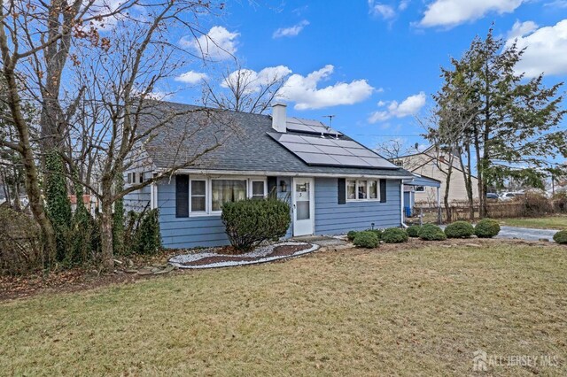 view of front of property with a front yard and solar panels