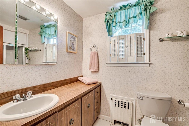 bathroom featuring toilet, vanity, and radiator heating unit