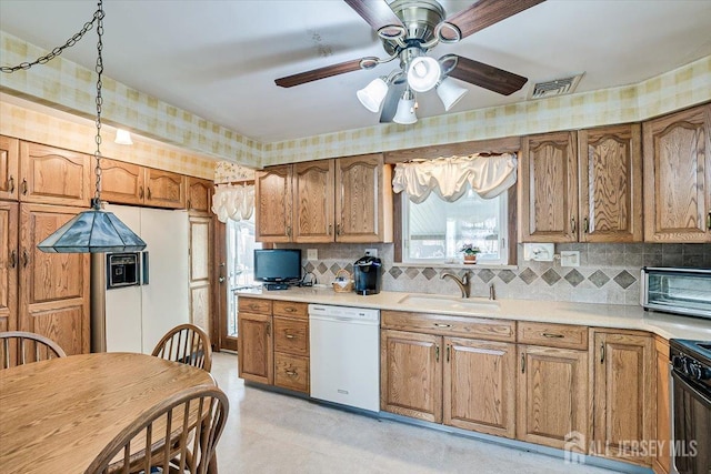 kitchen featuring tasteful backsplash, sink, stainless steel range, and white dishwasher