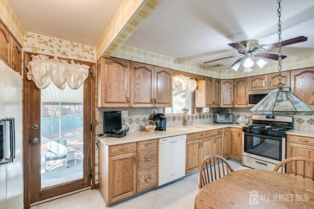 kitchen with a wealth of natural light, stainless steel appliances, ceiling fan, and tasteful backsplash