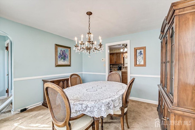 dining room with light carpet and a notable chandelier