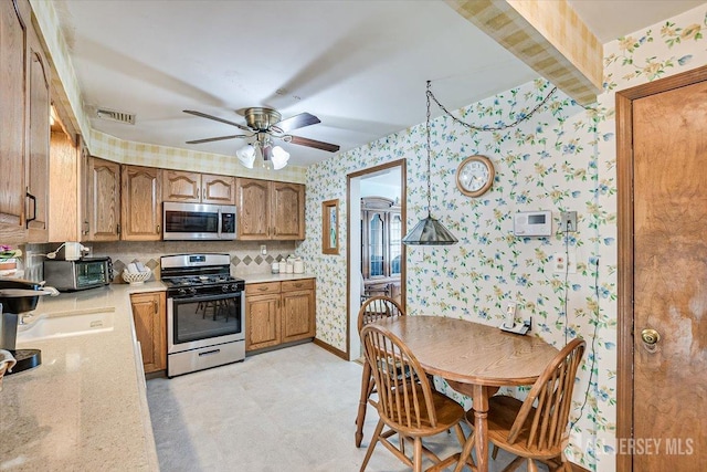 kitchen with appliances with stainless steel finishes, ceiling fan, and sink