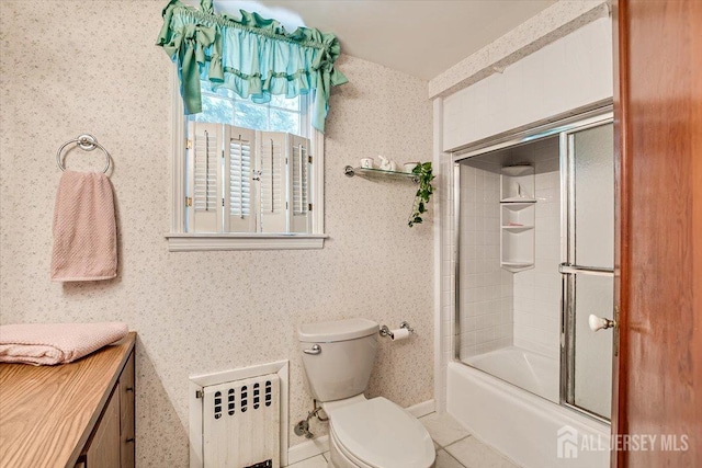 full bathroom with radiator heating unit, tile patterned floors, vanity, bath / shower combo with glass door, and toilet