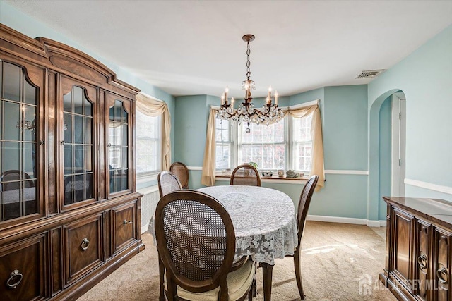 carpeted dining space with a chandelier