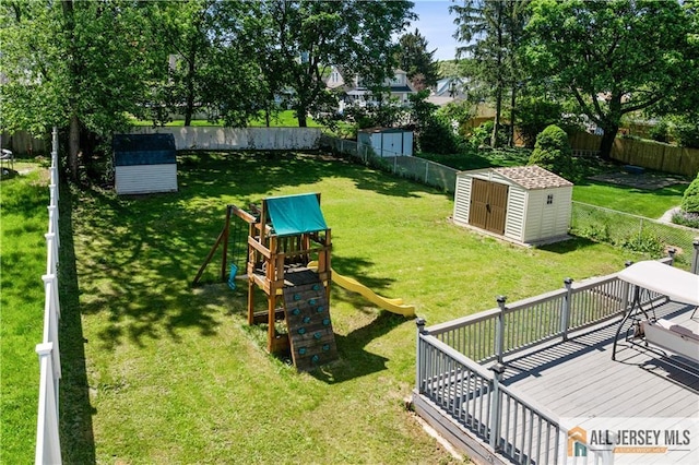 view of yard featuring a storage shed, a playground, an outbuilding, and a wooden deck