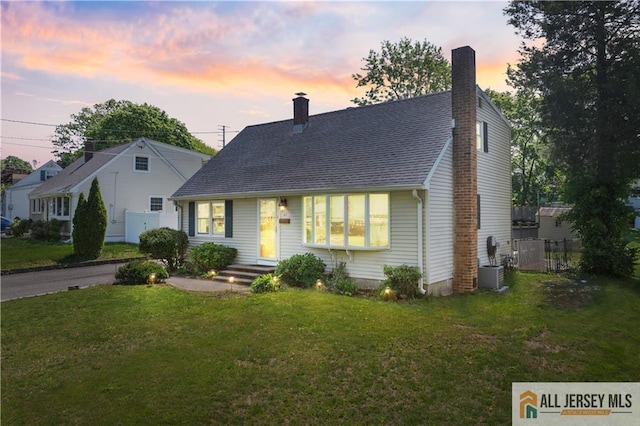 cape cod home featuring a chimney, central AC unit, and a shingled roof