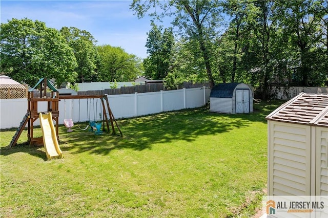 view of yard featuring a storage unit, a playground, an outdoor structure, and view of wooded area