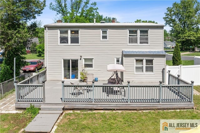 rear view of property featuring a chimney and a deck