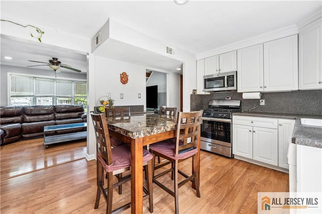 kitchen with stainless steel appliances, light wood-style flooring, and white cabinetry