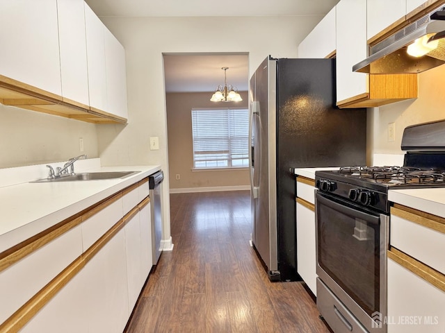 kitchen with a sink, stainless steel appliances, under cabinet range hood, white cabinetry, and a chandelier