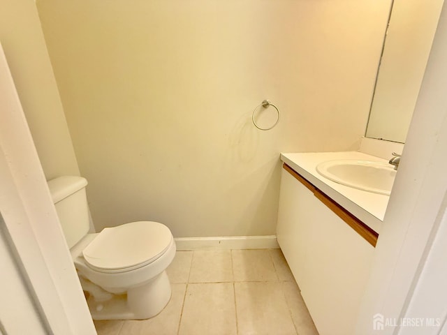 half bath with tile patterned floors, baseboards, toilet, and vanity