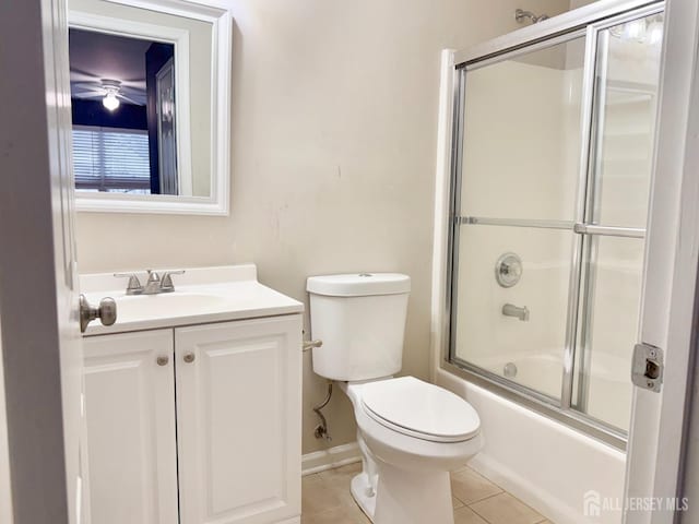 bathroom featuring tile patterned floors, toilet, shower / bath combination with glass door, baseboards, and vanity