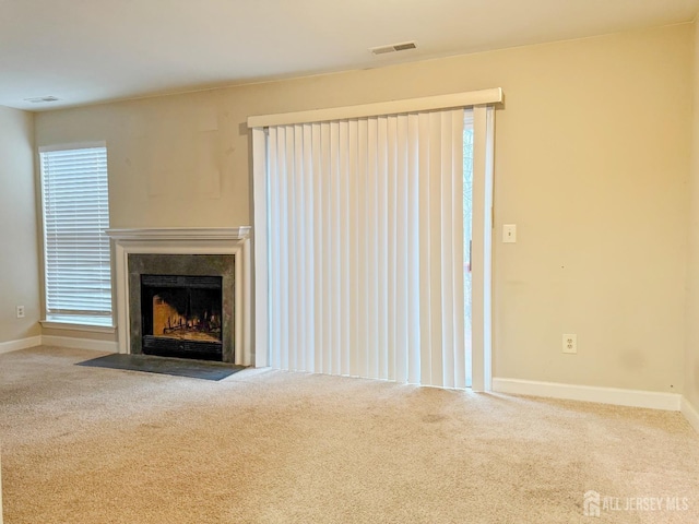 unfurnished living room with a fireplace with flush hearth, carpet, visible vents, and baseboards