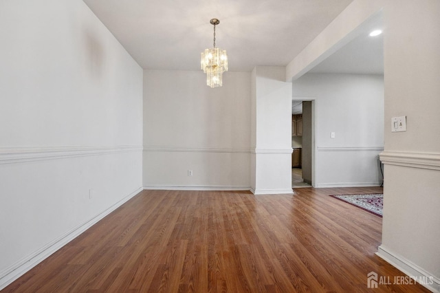 interior space with a notable chandelier, baseboards, and wood finished floors