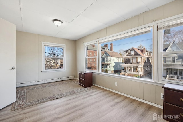 interior space with a baseboard heating unit and wood finished floors