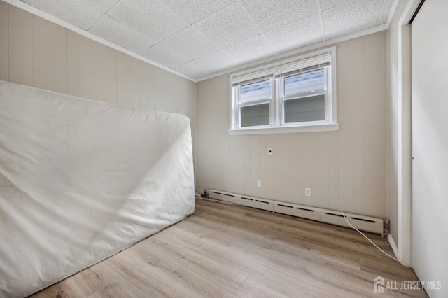 empty room featuring a baseboard heating unit and wood finished floors