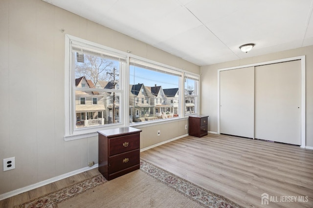 unfurnished bedroom with a closet, light wood-style flooring, and baseboards