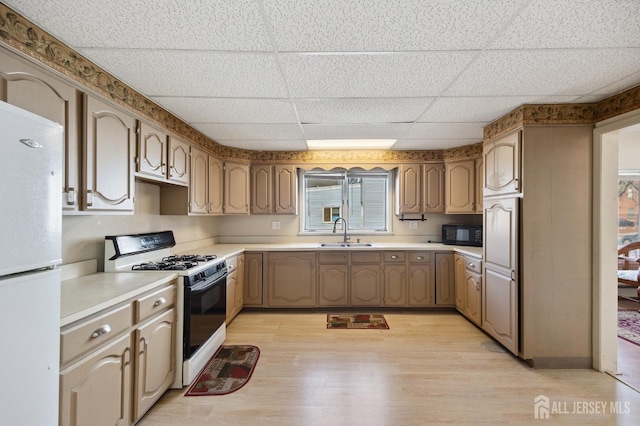 kitchen with range with gas cooktop, light wood-style floors, freestanding refrigerator, a sink, and black microwave