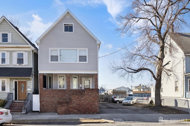 view of front of house featuring brick siding and fence