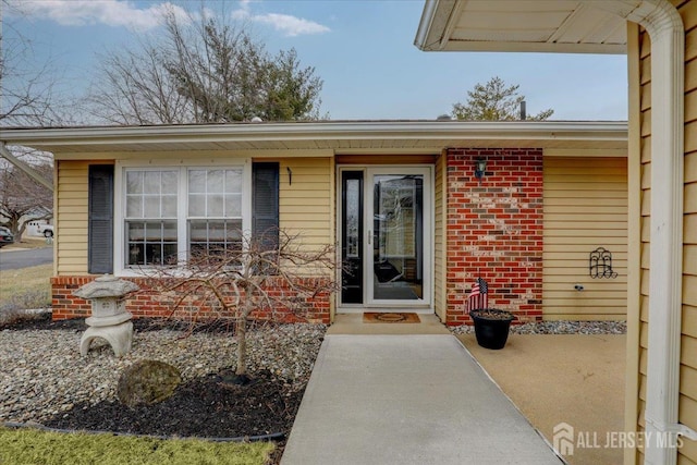 doorway to property featuring brick siding