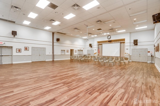 misc room featuring wood finished floors, visible vents, and a towering ceiling