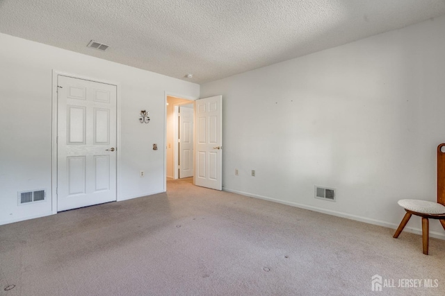 unfurnished bedroom featuring visible vents, light colored carpet, and a textured ceiling