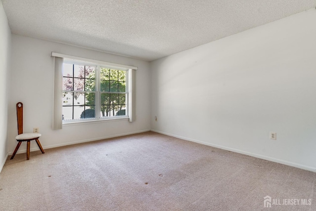 carpeted empty room with baseboards and a textured ceiling