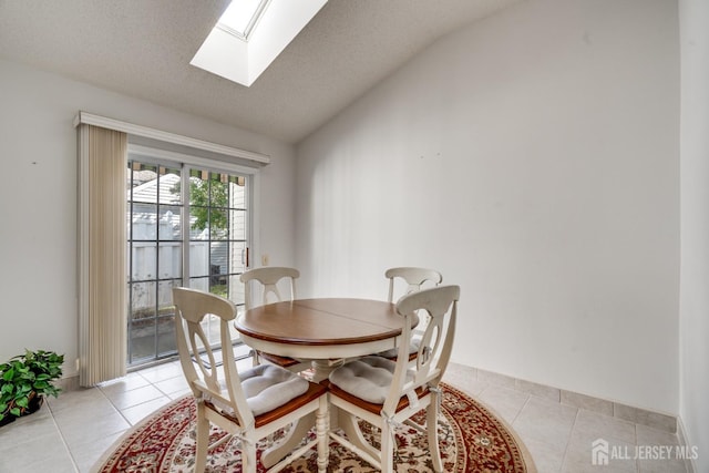 dining space featuring lofted ceiling with skylight, light tile patterned floors, and a textured ceiling