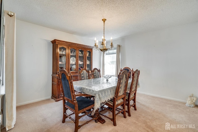 dining room with a notable chandelier, light colored carpet, and baseboards