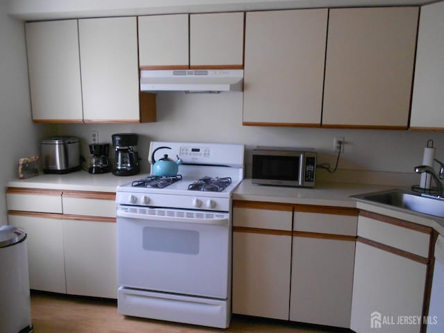 4222 N Bayberry Ct N, South Brunswick, NJ 08852 - kitchen featuring white gas range, under cabinet range hood, stainless steel microwave, light countertops, and white cabinets