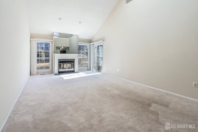 unfurnished living room featuring high vaulted ceiling and light colored carpet