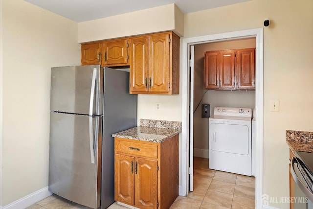 kitchen featuring washer / clothes dryer, light tile patterned flooring, stainless steel fridge, and light stone counters