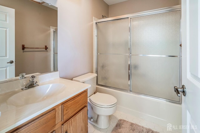 bathroom featuring vanity, toilet, combined bath / shower with glass door, and tile patterned floors