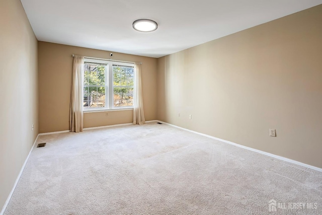 spare room with light carpet, baseboards, and visible vents